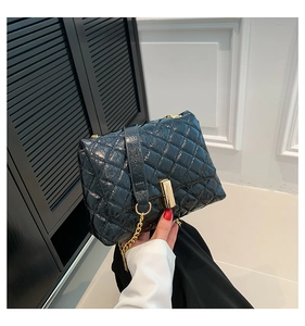 Close-up of quilted black leather texture with elegant gold metal lock and chain strap