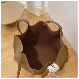 Detail of spacious interior with magnetic closure and decorative ribbon on brown tote bag