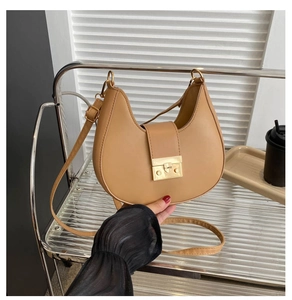 Detail of camel crescent bag featuring a gold metal buckle and smooth faux leather texture
