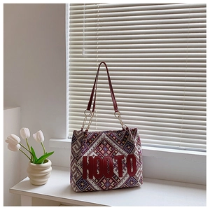 Detail of geometric jacquard tote bag featuring red HOOTO logo and gold chain strap