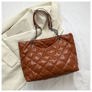 Gros plan d'un sac bandoulière matelassé marron avec chaînes et texture cuir brillant