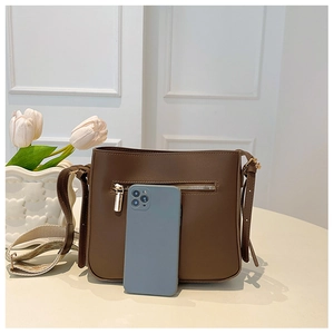 Brown matte leather bag with woven strap shown next to a smartphone for size scale