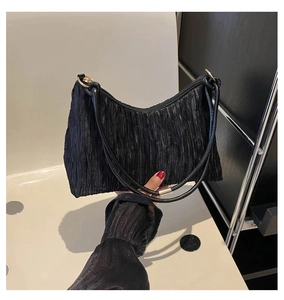 Détail d'un sac sous les aisselles en tissu plissé noir avec finition brillante et fermeture