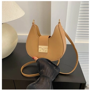 Close-up of minimalist crescent bag with golden metal clasp and adjustable leather strap