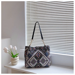 Detail of ethnic geometric embroidery on a large tote bag with leather straps and gold rings