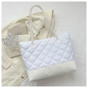 Dettaglio della borsa tote trapuntata bianca con base in pelle liscia su un blazer neutro
