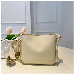 Detail of a creamy beige crossbody bag featuring an ethnic pattern wide fabric shoulder strap