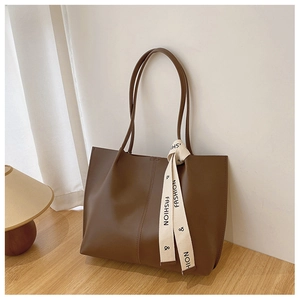 Detailed view of dark brown tote bag with leather texture and decorative ribbon