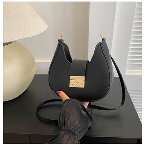 Detailed view of black crescent shoulder bag with vintage gold buckle and smooth leather