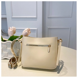 Detail of cream crossbody bag featuring a metal back zipper and vintage patterned strap