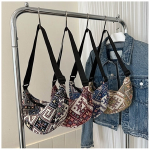 Detailed close-up of ethnic geometric pattern fabric crossbody bags with wide black straps
