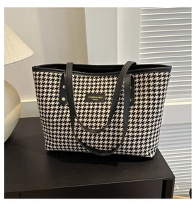 Detailed close-up of houndstooth tote bag with black leather trim and golden metal logo