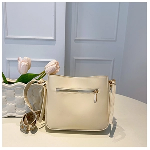 Detail of cream crossbody bag showing back gold zipper pocket and jacquard strap