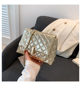 Detail of gold quilted chain bag with metallic texture and vintage finish on grey sofa