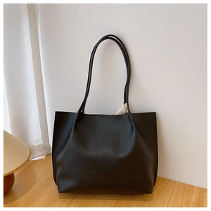 Detail of minimalist black tote bag with smooth texture and decorative silk scarf accent