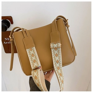 Detail of vintage brown leather handbag featuring an ethnic style wide woven shoulder strap