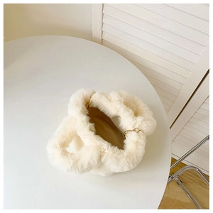 Détail du sac seau en peluche crème avec chaîne dorée et texture douce en fausse fourrure