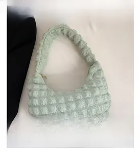 Detailed view of mint green bubble pleated fabric and golden zipper on hobo bag