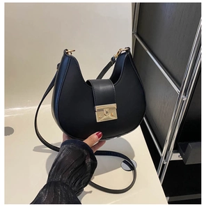 Detail of black crescent hobo bag with large gold metallic buckle and fine strap