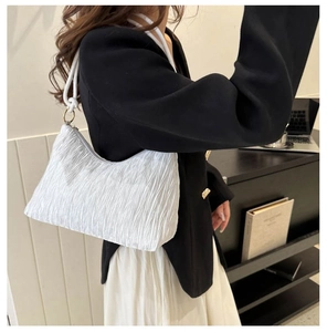 Détail du sac à bandoulière blanc plissé avec poignée en corde nouée et anneaux dorés