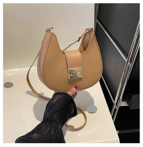 Handheld view of a khaki crescent shoulder bag with golden metallic buckle detail