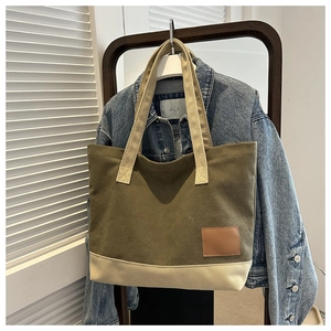 Dettaglio della borsa tote in tela verde oliva e beige con inserto in pelle marrone