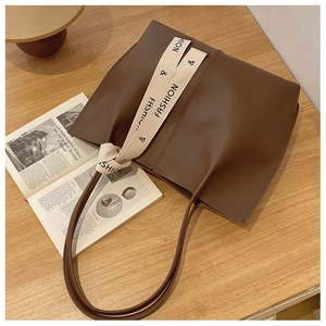 Detail of dark brown tote bag with fashion canvas strap on a wooden table