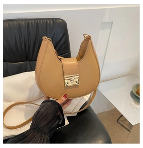 Detailed view of camel hobo crescent bag with gold buckle on a black leather chair