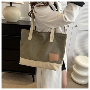 Dettaglio della borsa shopper in tela con design patchwork verde e beige e patch in pelle