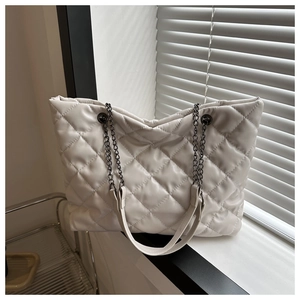 Gros plan d'un sac cabas matelassé blanc avec bandoulière près d'une fenêtre