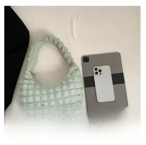 Macro view of mint green bubble pleat texture bag with tablet and phone for size comparison