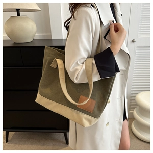 Dettaglio laterale di una borsa tote in tela verde oliva indossata da una modella chic