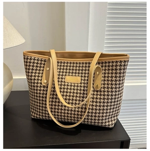 Close-up of houndstooth tote bag detail featuring premium fabric and metal logo plate