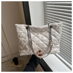 Détail du cabas matelassé blanc avec bandoulière chaîne argentée et texture douce