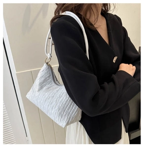 Détail du sac plissé argenté avec poignée ronde et fermeture éclair métallique robuste
