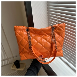 Détail d'un sac cabas matelassé orange vif avec chaîne en métal et bandoulière