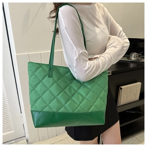 Dettaglio della borsa shopper trapuntata verde fluo in nylon con base in pelle su modella