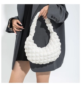 Detail of white bubble textured hobo bag carried by a model in a grey blazer
