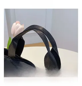 Détail de la poignée en tissu noir renforcé et du motif à losanges sur le sac cabas