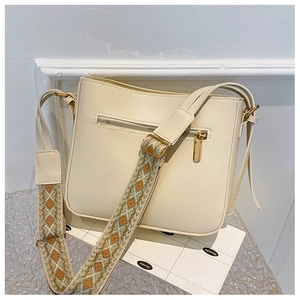 Detail of off-white crossbody bag featuring a bohemian wide strap and golden zipper pocket