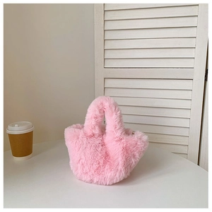Détail d'un sac seau rose en fausse fourrure pelucheuse sur une table blanche
