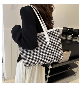 Close-up of houndstooth tote bag featuring white leather handles and spacious interior
