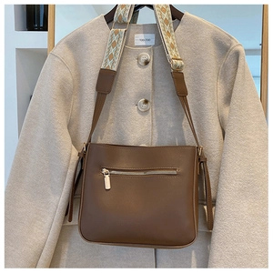 Detail of brown leather crossbody bag with colorful geometric woven wide shoulder strap