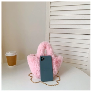 Mini sac seau en peluche rose avec chaîne dorée présenté à côté d'un smartphone