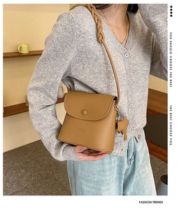 Detail of brown litchi pattern leather shoulder bag featuring unique elephant charm