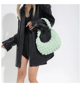 Detail of mint green ruched cloud bag with textured bubble fabric on a model