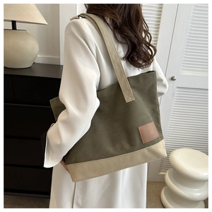 Vista posteriore di una modella con borsa tote in tela verde oliva e beige in un interno