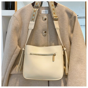 Detail of cream crossbody bag with ethnic jacquard strap and leather tassels on coat