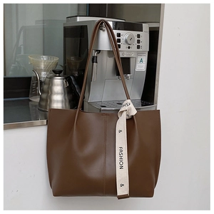 Detail of dark brown matte leather tote bag featuring stylish ribbon and vertical stitching
