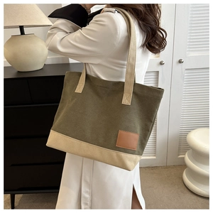 Dettaglio della borsa tote in tela bicolore con toppa logo in pelle marrone